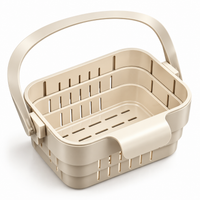 Panier égouttoir beige avec anse relevée, structure pliable à trois niveaux, vu en angle sur fond blanc.