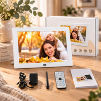 Cadre photo numérique blanc avec sa boîte, le chargeur, le support, la télécommande et le manuel fournis.